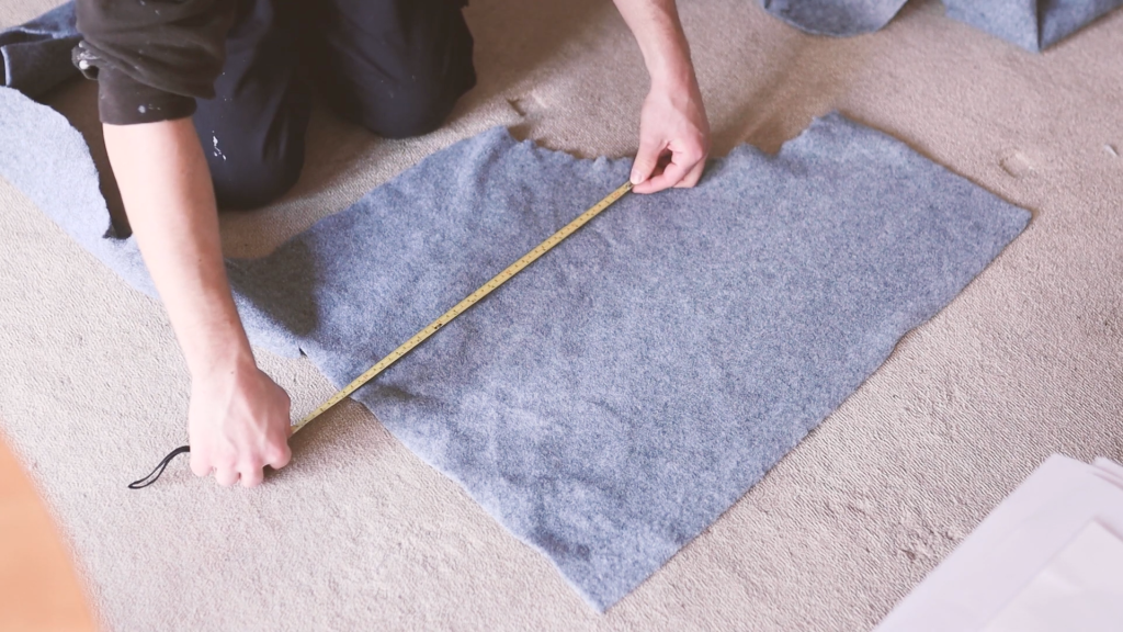 Measuring scraps of mid-grey van carpet on the floor