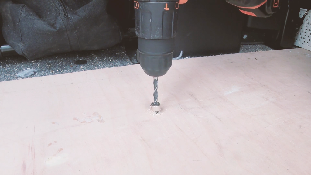 The drill making a hole through the van floor