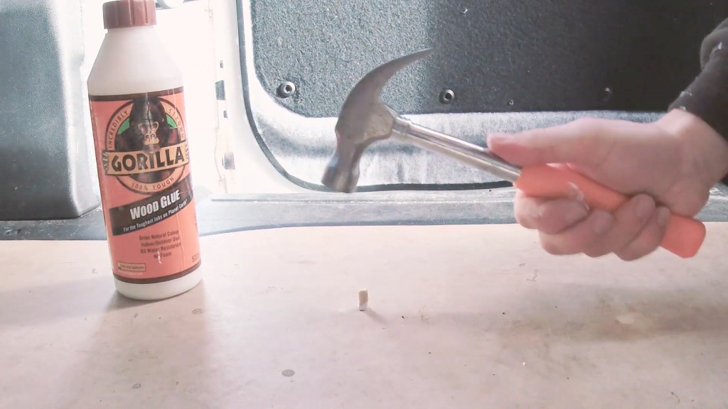 Hammering a glued wooden dowel into the van floor