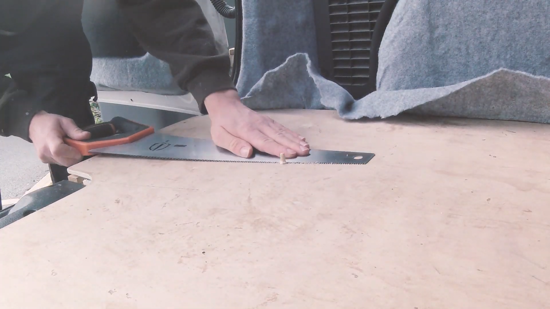 A saw cutting the tops off the wooden dowels