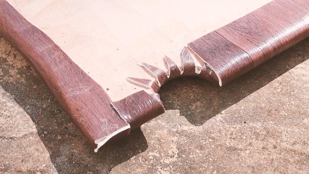 Close-up of the vinyl edge stuck to the underside of the plywood van floor